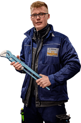 Mitarbeiter in blauer Arbeitskleidung hält eine große Rohrzange in den Händen, Namensschild 'A. Bußmann' sichtbar.