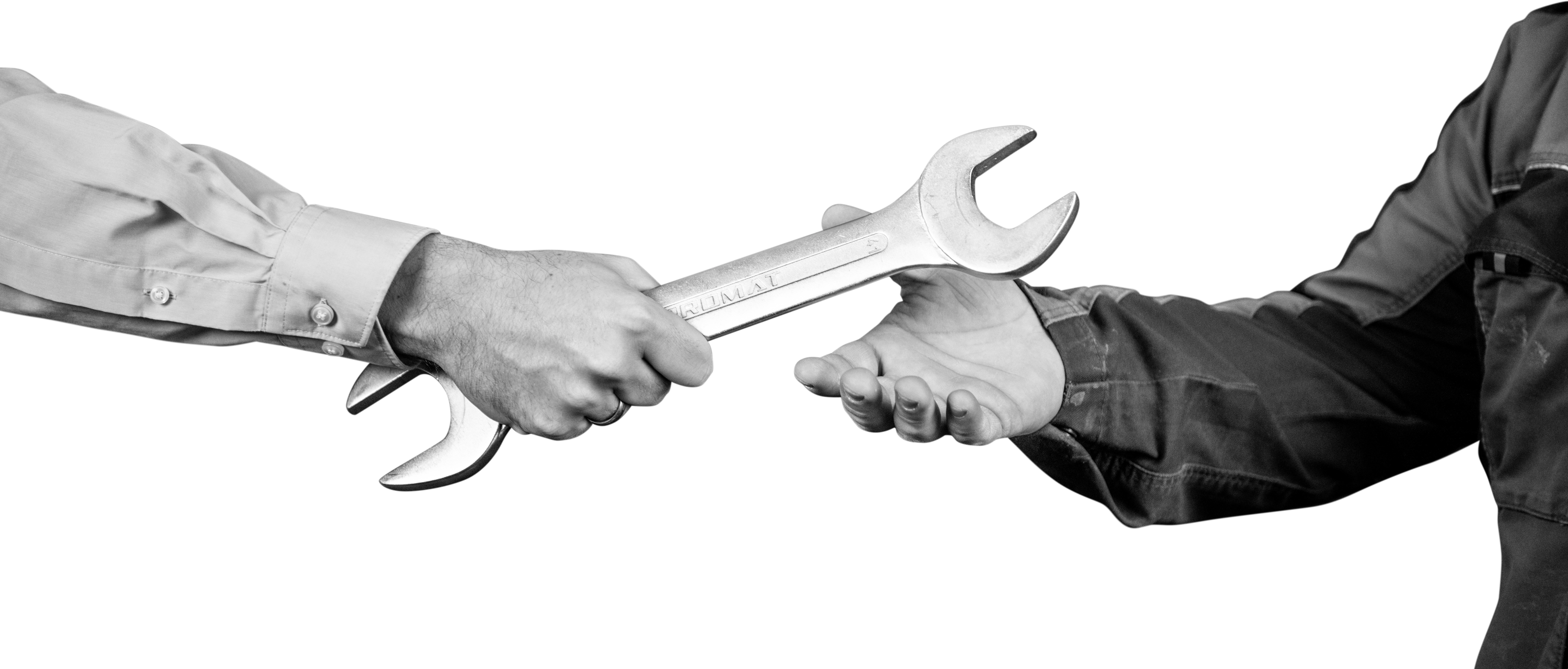 Symbolisches Bild: Eine Hand im Hemd übergibt einen Schraubenschlüssel an eine Hand in Arbeitskleidung.